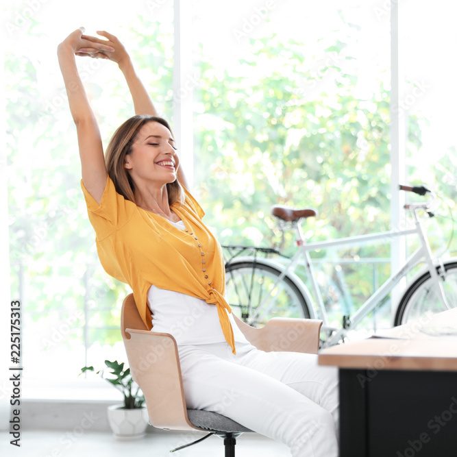 Eine zufrieden aussehende Frau steckt sich auf einem Bürostuhl.