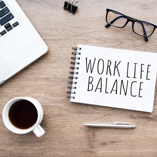 Schreibtisch mit Laptop, Kaffee und Block mit Work Life Balance drauf.