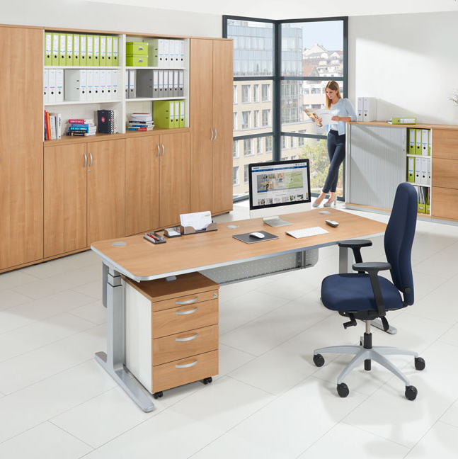 Bürolandschaft mit höhenverstellbarem Schreibtisch, Rollcontainer, Schränken und Regalen in Nussdekor und einem blauen Bürostuhl.
