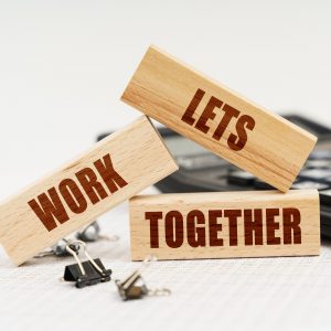 Beschriftete Holzstücke auf einem Tisch mit Let's work together drauf.