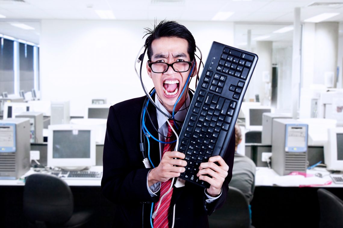 Verrückter Geschäftsmann hält Tastatur und Kabel im Büro